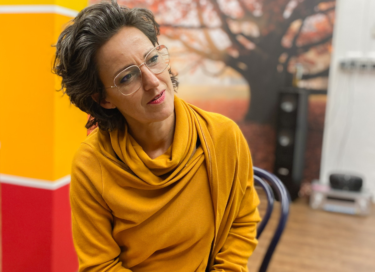 Oberkörper einer Frau. Martina Model im Forum für Schönheit, sitzt auf einem Stuhl. Warme rote und gelbe Farb-Töne im Hintergrund.