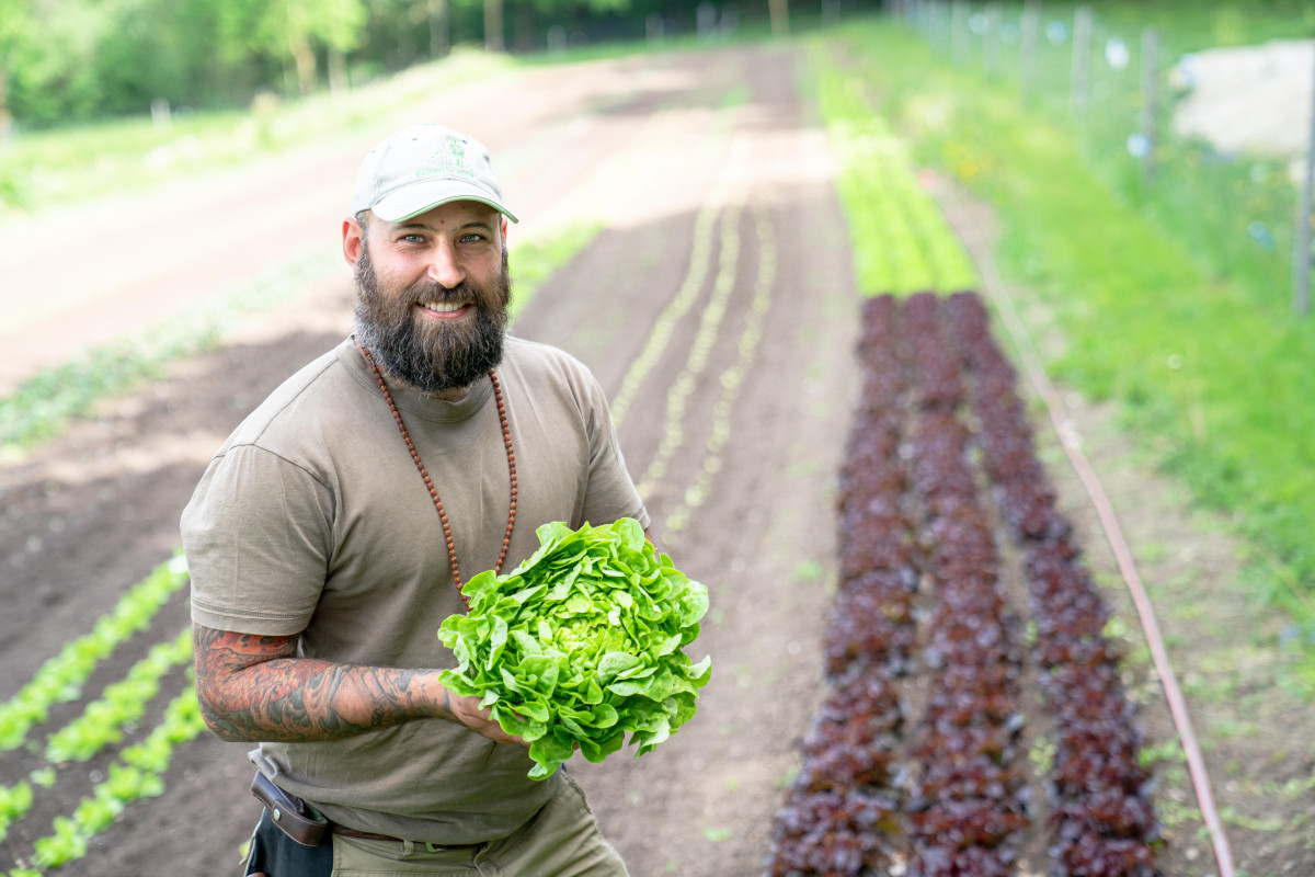 Florian Blank im Porträt vor einem Salatbeet