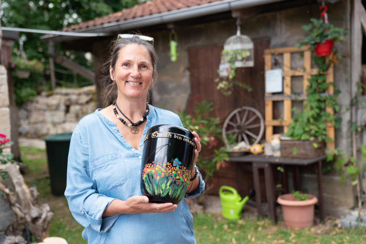 Elke Zaska im Garten mit einer selbst gestalteten Urne