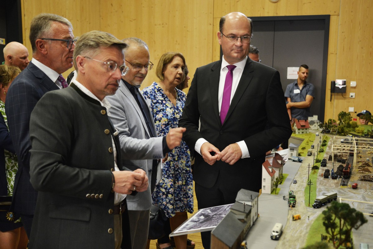 Behördenleiter Kurt Hillinger erläutert Staatsminister Albert Füracker anhand eines historischen Modells des ehemaligen Bahn-Areals, wo sich das Amtsgebäude heute befindet.