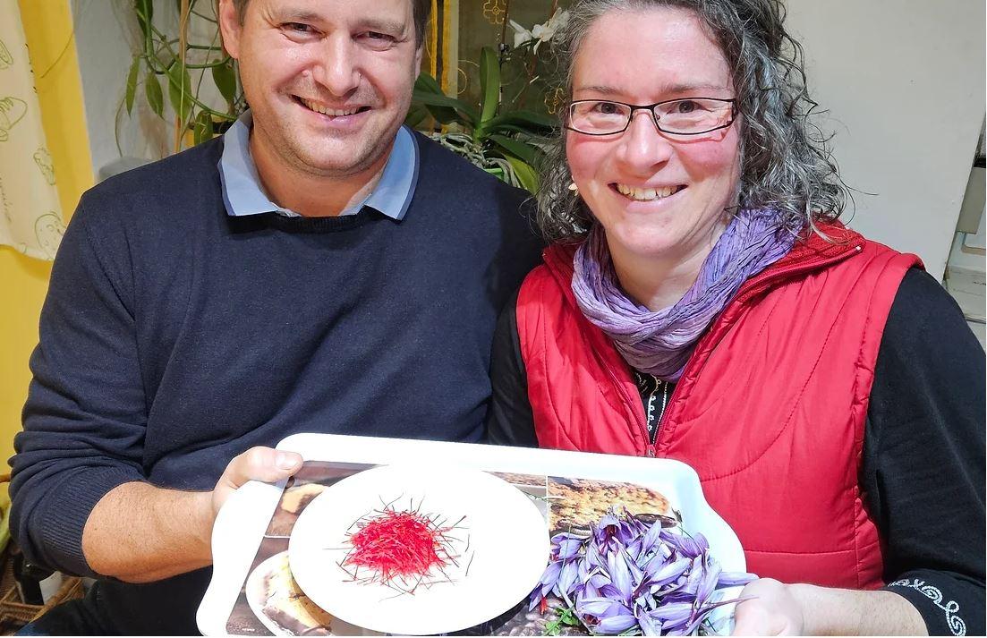 Ein Mann und eine Frau mit einem Teller voller Safran-Fäden und -Blüten