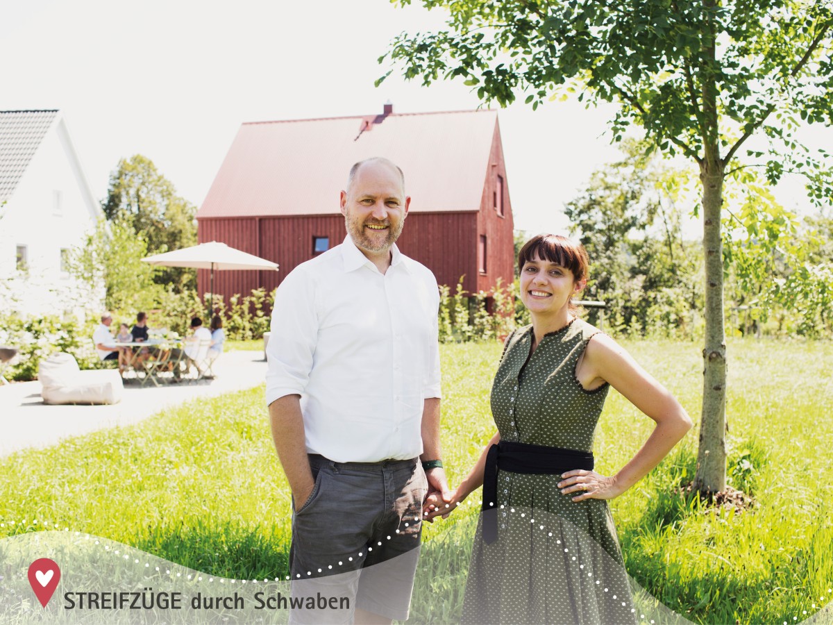 Julia und Michael Staudinger stehen im Garten, im Hintergrund das alte Bauernhaus mit D'Kammer und ihr rotes Wohnhaus