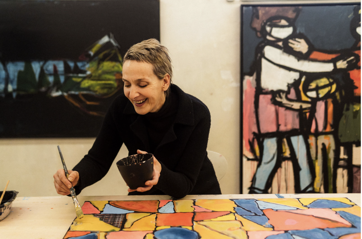 Eine Frau im schwarzen Pullover und Pinsel in der Hand malt ein Bild