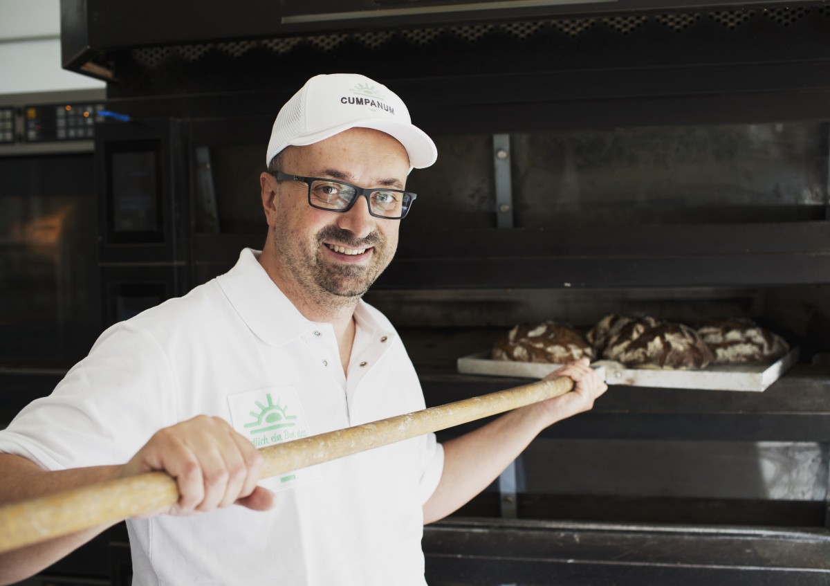 Ein Bäckermeister und HeimatUnternehmer holt Brot aus dem Ofen