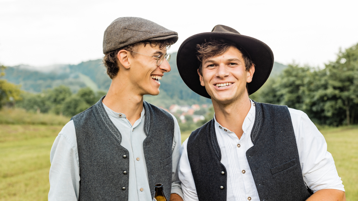 Auf dem Bild sieht man zwei junge Männer vor der Rhön-Landschaft - Marc-André und sein Bruder Florian haben zusammen die "Rhönmomente"  gegründet.