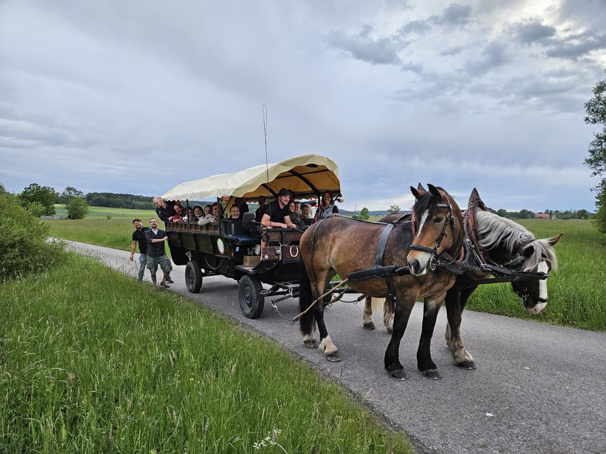 Eine Pferdekutsche steht auf einem Feldweg mit 18 gutgelaunten Personen darauf, die bei diesem Treffen der HeimatUnternehmen MittelFranken dabei waren.