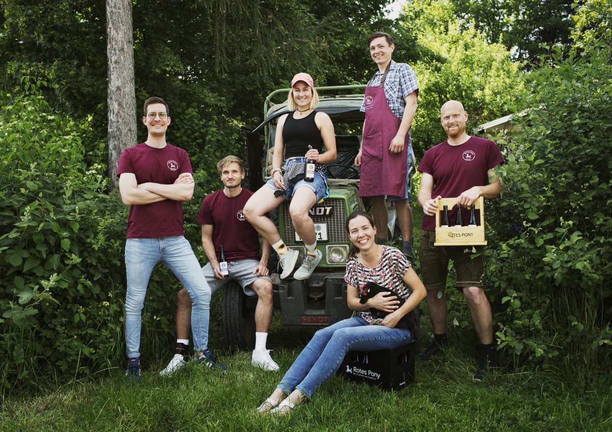 Junge bayerische, von HeimatUnternehmen Bayern geförderte Unternehmer sind vor einem Traktor zu sehen