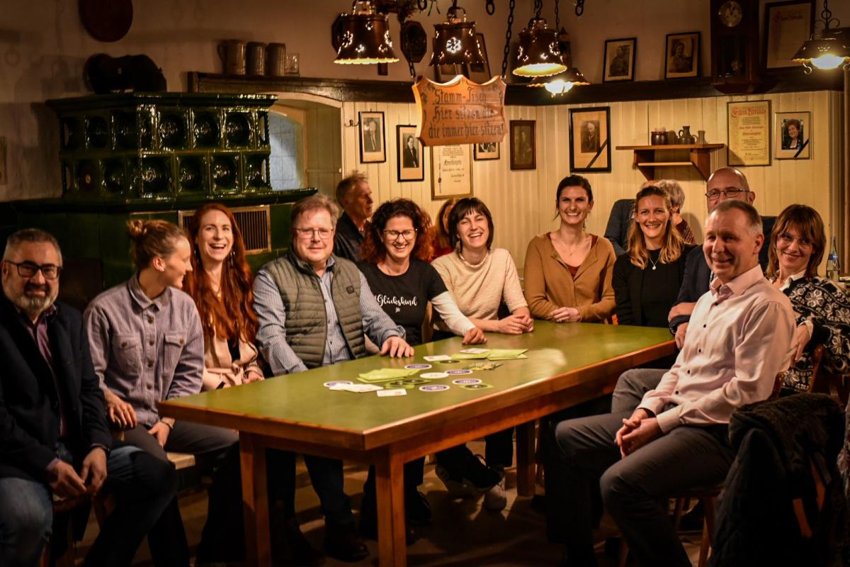 Eine Gruppe von Menschen sitzt in einem Gasthaus an einem Tisch