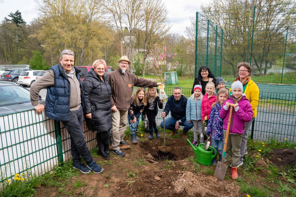 Erwachsene und Kinder posieren vor dem Pfirsichbaum